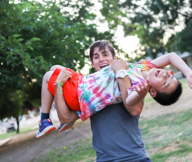 Instructor smiling and carrying a camper.