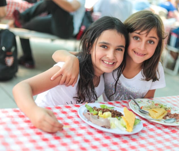 Two campers smiling at dining table.