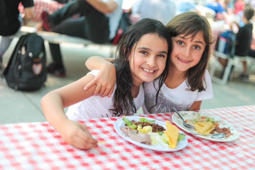 Two campers smiling at dining table.