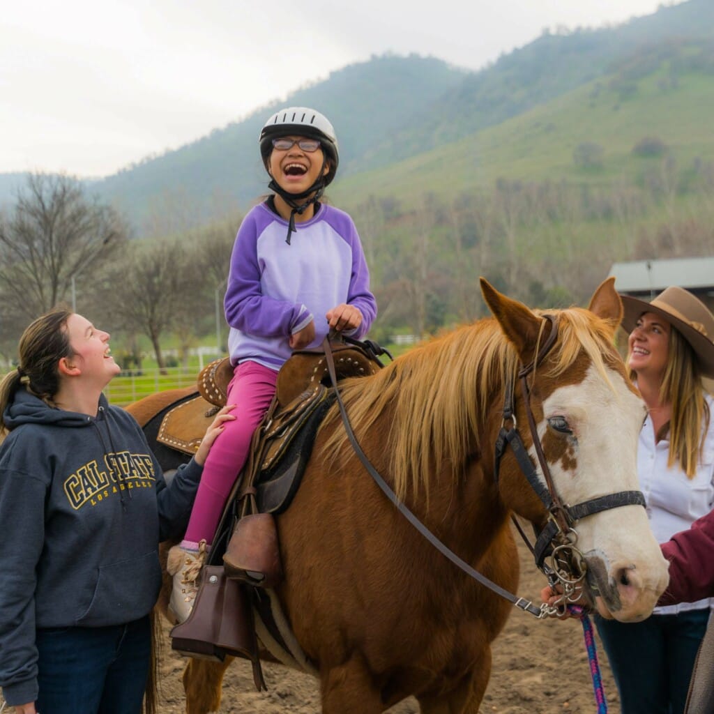 Girl laughing on horse.