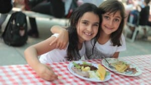 Two campers smiling and eating lunch together.