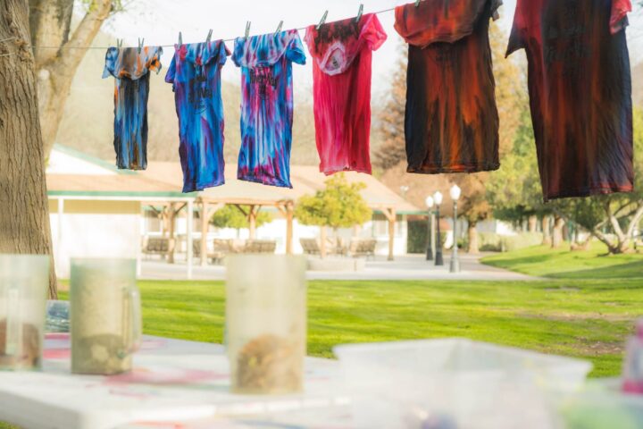 Tie-dye shirts hang to dry on a line, showcasing the results of Outdoor STEAM Activities.
