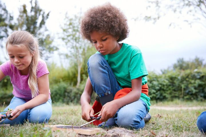 Children practice fire-starting skills in a field during outdoor learning activities.